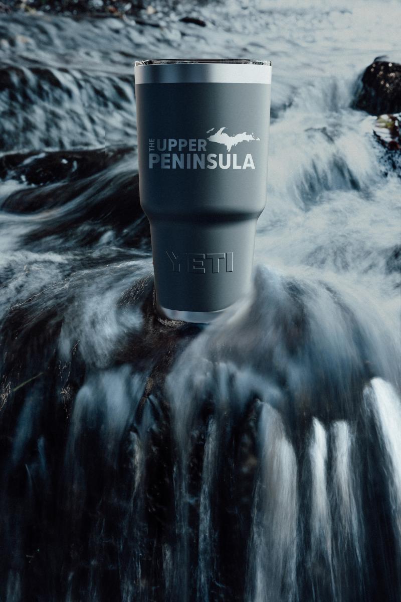 UP branded Yeti sitting in a waterfall