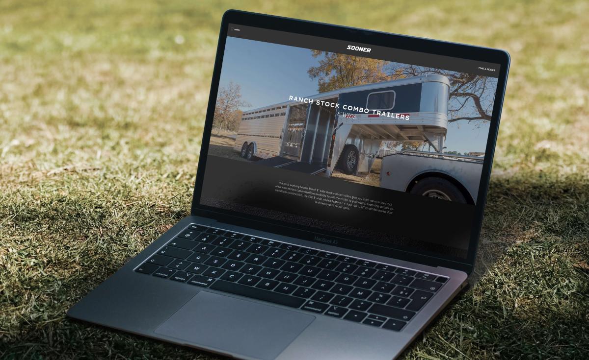 a laptop sitting in the grass with a Sooner Trailer page on screen