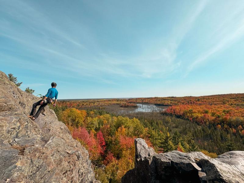 a climber taking a break on Sluggs Bluff in the U.P. looking out at the autumn forest