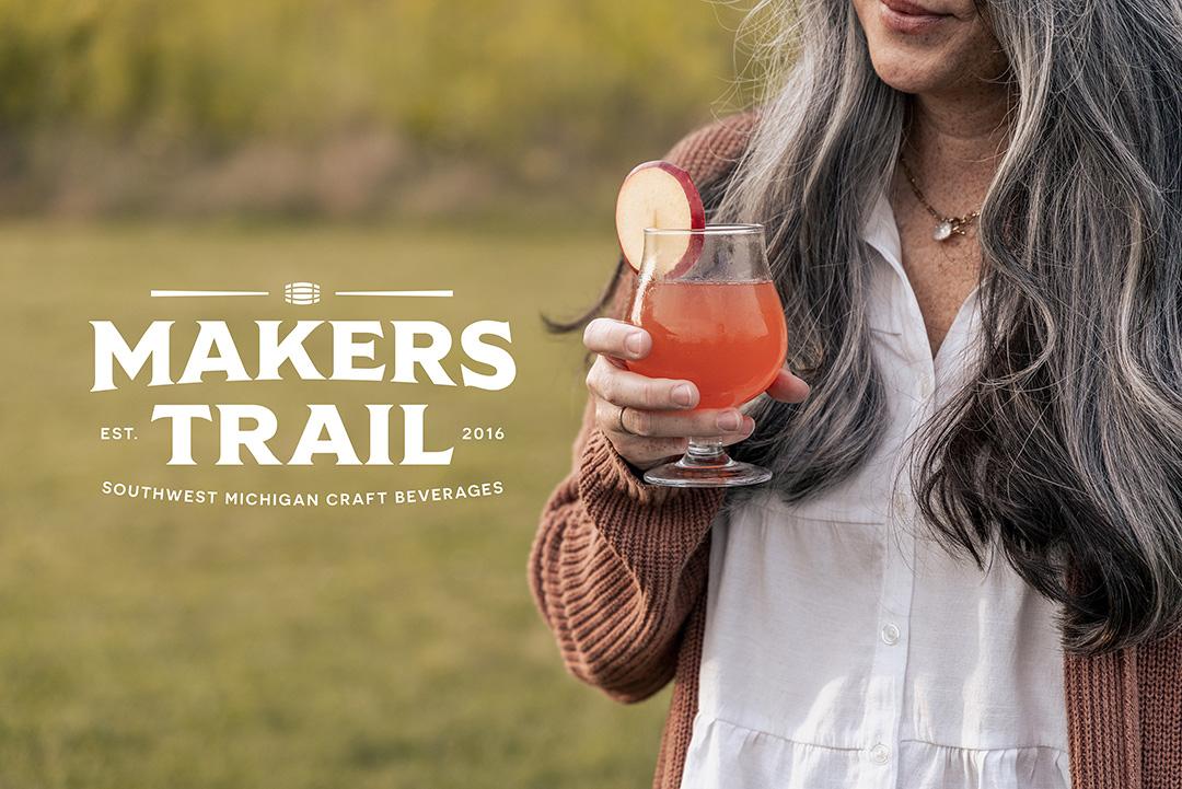 Maker’s Trail logo over a woman holding a craft drink outdoors