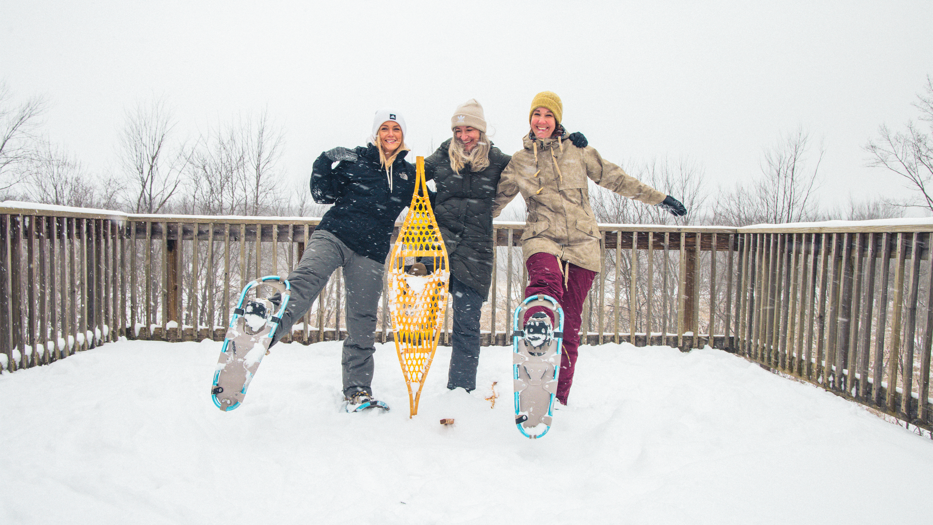 Friends smiling while they show their snowshoes